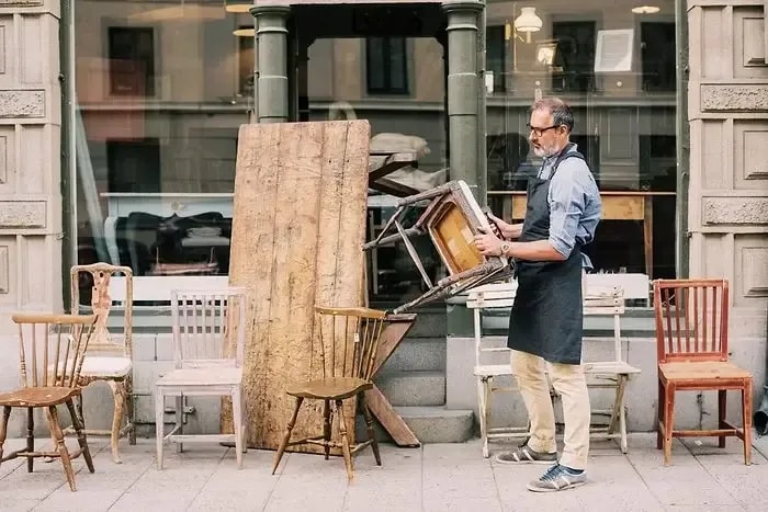 man outside selling used chairs and tables