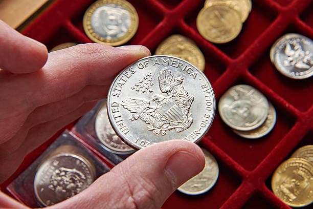holding silver coin above coin storage box
